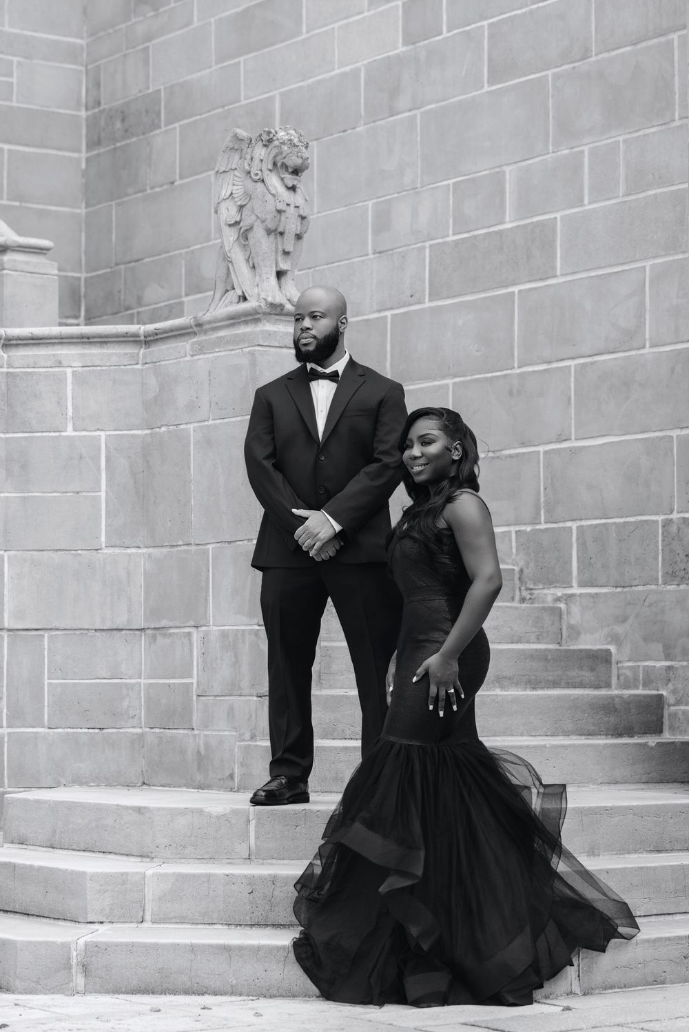 Couple standing against a stone wall in evening dress