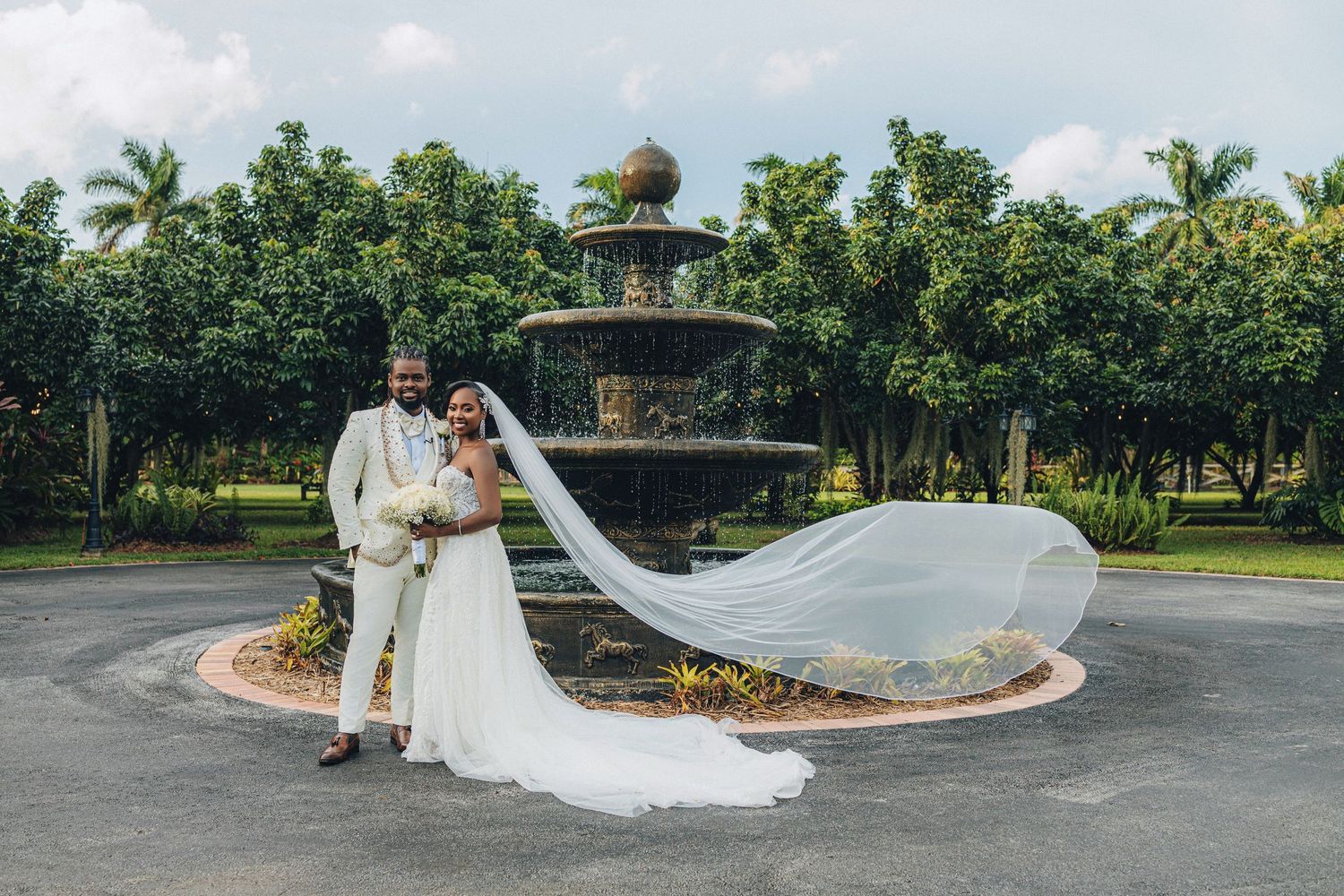 Bride with her veil carried across the lawn